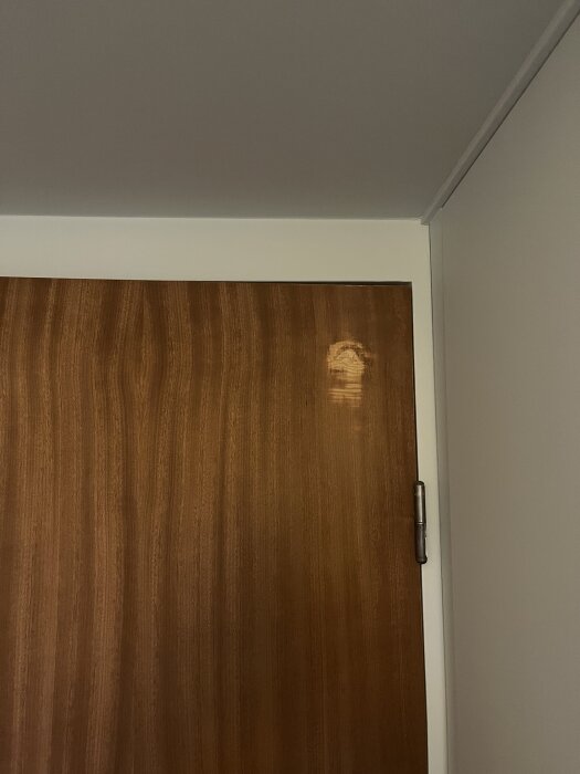 Trädörr med slipmärken på ytan, särskilt synligt i det övre högra hörnet.