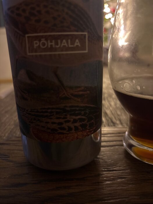 En flaska öl med etiketten "Pöhjala Rukkirääk" bredvid ett halvtomt glas på ett träbord.