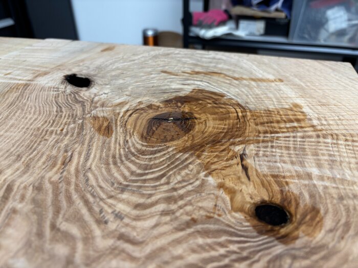 Träyta med en mörk fläck av epoxy i mitten, visar pågående härdningsprocess.