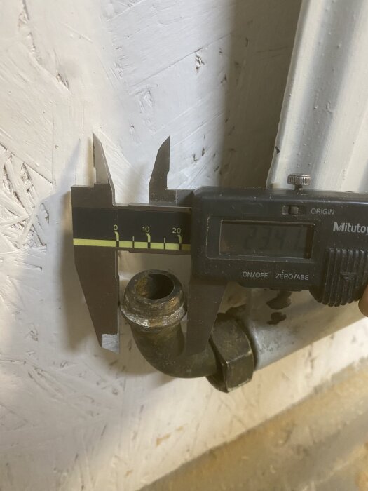 Närbild på ett elementrör med en mässingsdel och ett digitalt skjutmått som visar 23,41 mm, för att hitta rätt koppling.