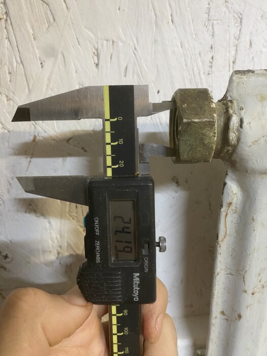 Digital skjutmått som mäter en mässingskoppling på ett element, visar 24,19 mm. Mässingsdelen är felstegrad och passar inte röret.