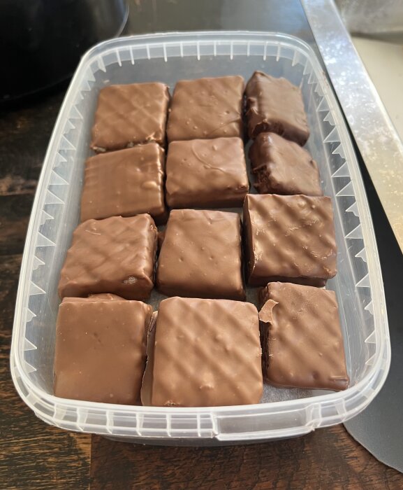 Hemgjorda kexchoklad med jordnötssmör i en plastburk, redo för julen. Täckt i choklad, placerade i rader.