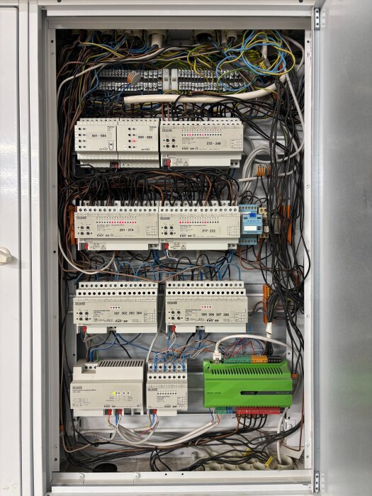 KNX-central med två dimmeraktorer och flera ledningsanslutningar, inuti ett öppet skåp med många kablar och elektriska komponenter.