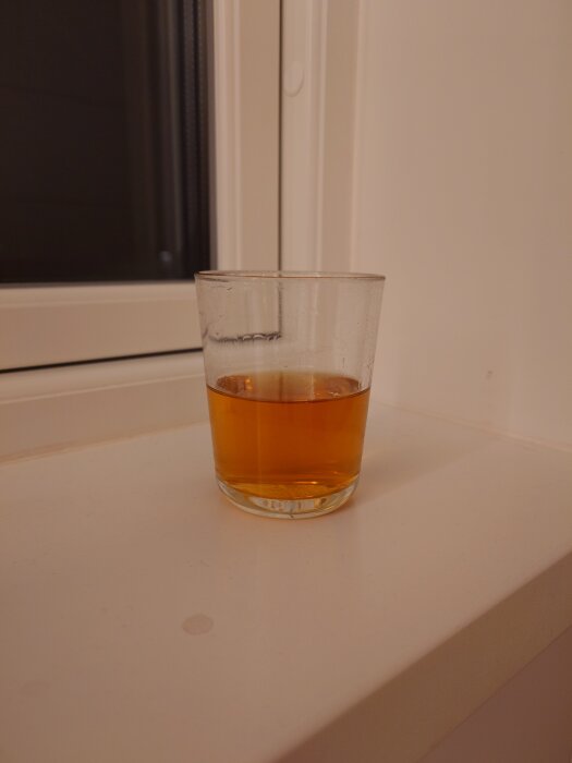 Glas med Laphroaig whisky mot fönsterbräda i badrum.