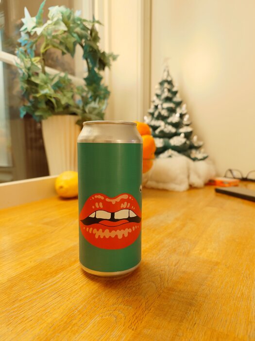 En burk med Omnipollo-lager står på ett bord, dekorerad med ett tryck av stora röda läppar.