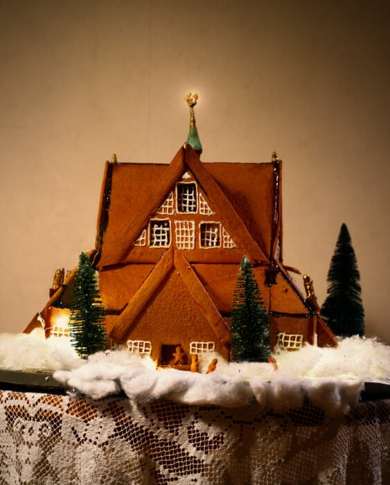 Pepparkakshus föreställande Kiruna kyrka i miniatyr, dekorerat med marsipanskulpturer och konstgjorda granar, upplyst med ytterbelysning.
