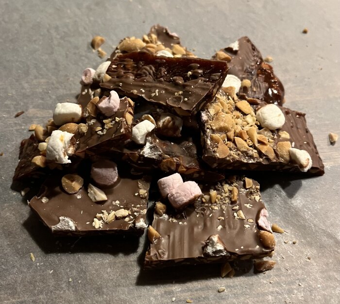 Chokladbitar med krossade nötter och marshmallows på en rustik yta.
