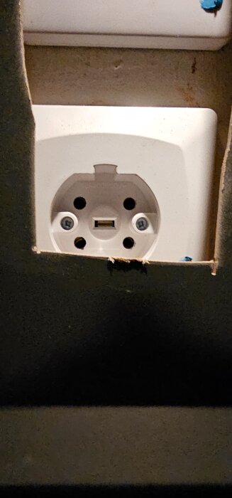 Trefasuttag inuti ett skåp med synliga kabelanslutningar, del av köksrenoveringsprojekt.