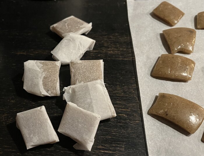 Hemgjord lakritskola inslagen i bakplåtspapper och några oknäckta bitar på bakplåtspapper.