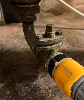 Fyrkantig tapp på ett rör som behöver vridas ett kvarts varv, nära en gul slangkoppling.