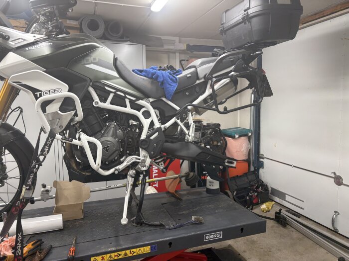 Motorcykel på lyft med ny kedja och drev, verktyg runtomkring.