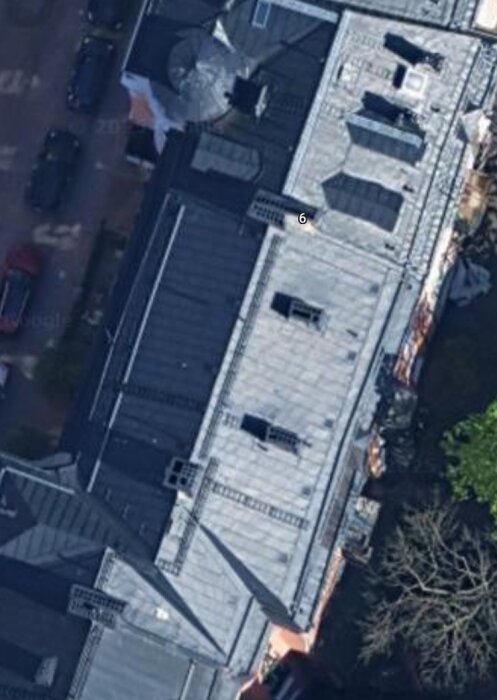 Flygfoto av ett tak på en byggnad i en trång stadsmiljö, med flera ventilationsutgångar synliga på taket.