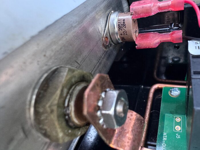 Närbild av en säkerhetsgivare ansluten med röda kabelskor till ett kretskort, vid sidan av en metallkonstruktion.