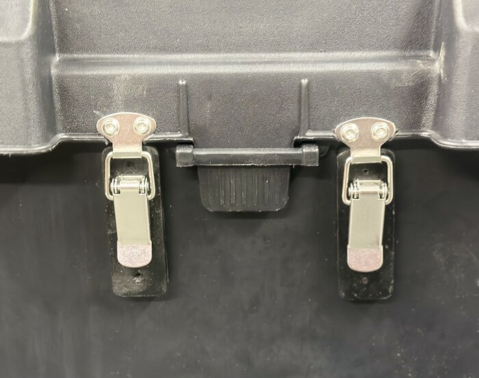 Svart batterilåda med två rostfria lås i metall för säker förslutning, monterad på toppen.