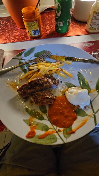 Grillad Secreto de Iberico serverad med pommes frites, aioli och mojo rojo på en tallrik, med en dryck i bakgrunden.
