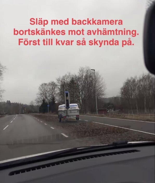 Släp med backkamera står vid sidan av en landsväg, erbjuds gratis mot avhämtning enligt texten i bilden.
