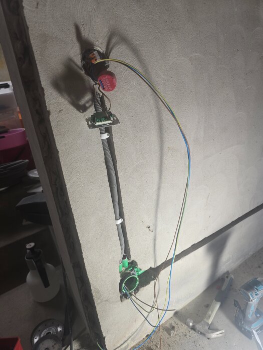 Elektrisk installation i en vägg med öppet doslock, synliga elledningar och flexrör. Verktyg och utrustning syns i förgrunden.