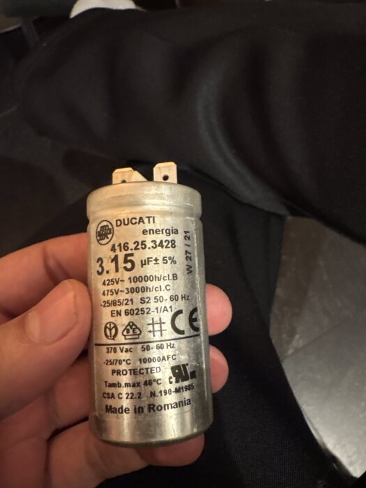Kondensator från en fläkt med märkningen "Ducati energia 3.15 µF ±5%" i en hand, potentiellt orsak till fläkts problem.
