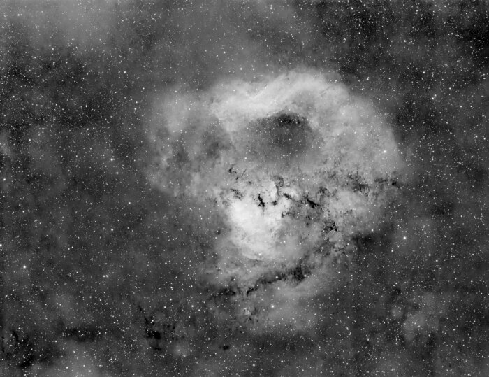 Svartvit bild av en nebulosa med ett molnliknande utseende omgiven av stjärnor i rymden.