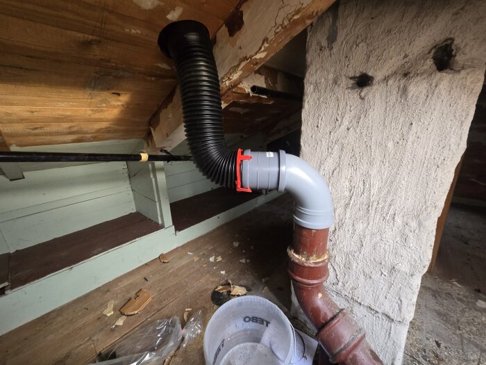 Rörinstallation i tak, svart spirorör anslutet till grått och rostbrunt rör, relaterat till avloppsluftare och avloppsluktproblem.