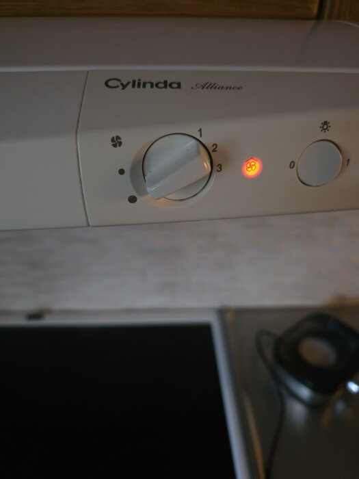 Köksfläkt av märket Cylinda Alliance med vred inställt på läge tre; en röd lampa lyser bredvid inställningarna.