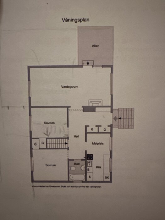 Planritning av våningsplan för ett hus med två sovrum, kök, vardagsrum, badrum, hall och matplats, samt altan.