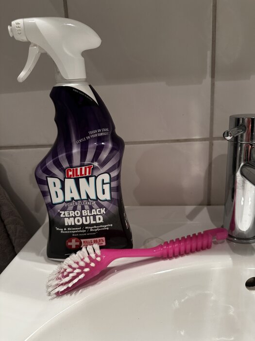 Rengöringsmedel Cillit Bang och rosa borste på ett handfat i badrummet.