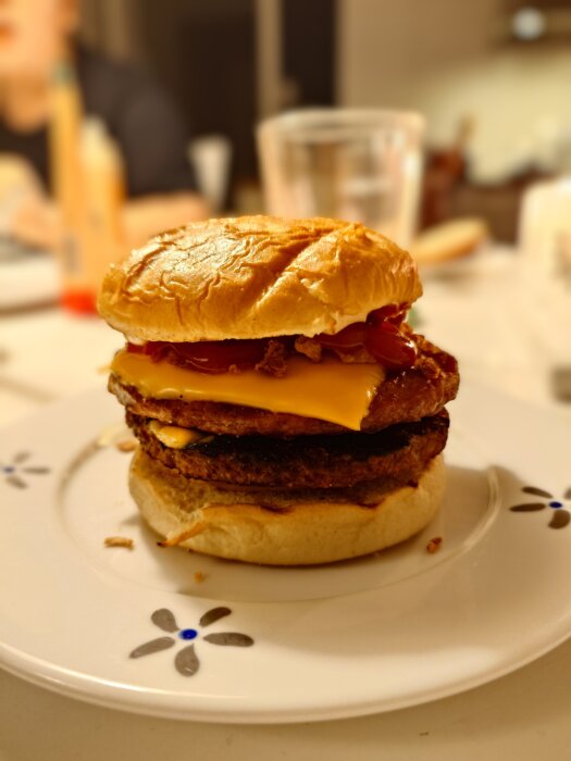 Dubbel hamburgare med ost och ketchup på en dekorerad tallrik.