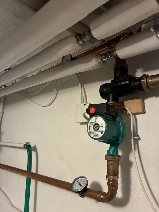 Uppvärmningssystem med rör och cirkulationspump, två tryckmätare synliga.