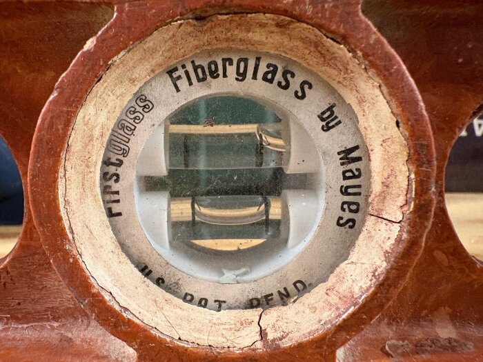 Närbild av ett gammalt vattenpass från 50- eller 60-talet, med texten "Fiberglass by Mayes" runt libellen.