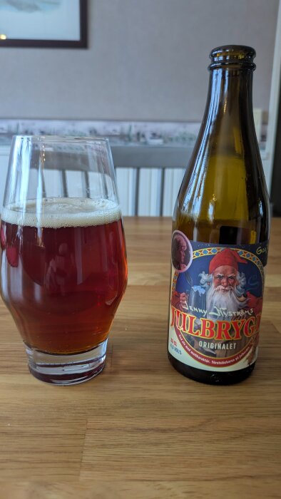 Julöl på bordet med en glasflaska och ett glas fyllt med den mörkröda drycken bredvid.