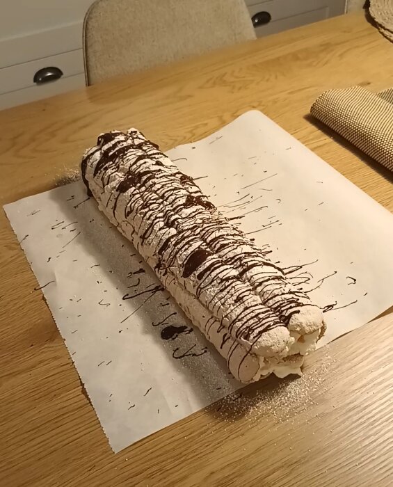 En Budapeststubbe ligger på bakplåtspapper, dekorerad med choklad och florsocker, klar att serveras till julfirandet.