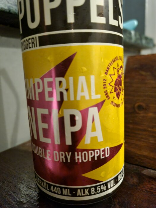 Flaska med etikett "Poppels Imperial NEIPA, Double Dry Hopped", alkoholhalt 8,5%, står på en träyta.