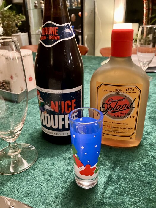 Flaska med Brune Houffebrygd och flaska med Gammel Opland Akvavit på ett bord med grön duk, tillsammans med ett färgglatt snapsglas.