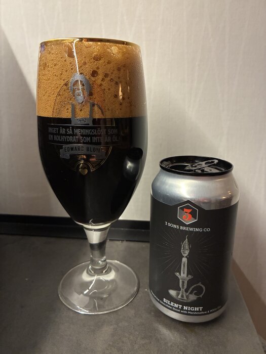 Ett glas mörk öl från 3 Sons Brewing Co med etiketten "Silent Night" och en burk bredvid.