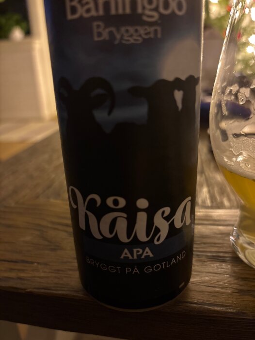 Flaska med Kåsa APA öl från Båthingoo Bryggeri, bryggt på Gotland, bredvid ett glas öl i skymd miljö.
