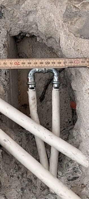 Vita rör med metallbeslag är ingjutna i betong; en linjal mäter avståndet. Fråga om risk för nötningsskador och läckage i inlägget.