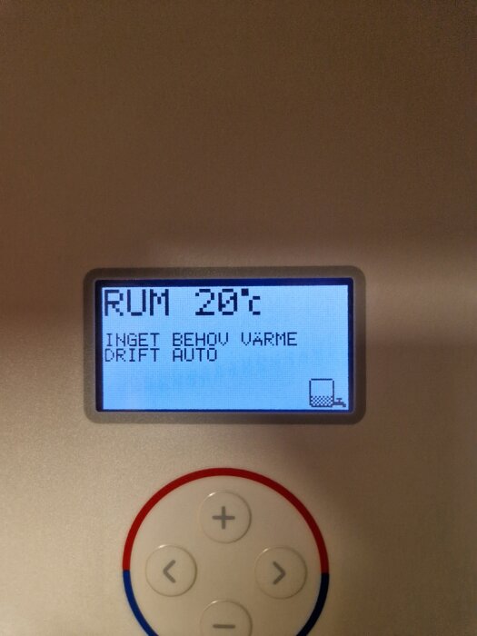 Display på en termostat visar "Rum 20°C, inget behov värme, drift auto" med kontrollknappar under.
