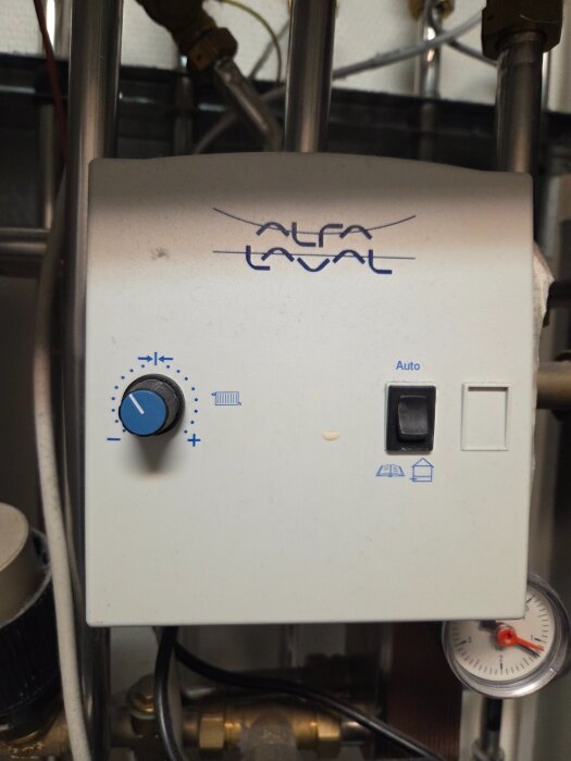 Fjärrvärmeanläggning med Alfa Laval-ställpanel, inklusive vred för justering och mätare. Fokus på inställningar för golvvärme och element.
