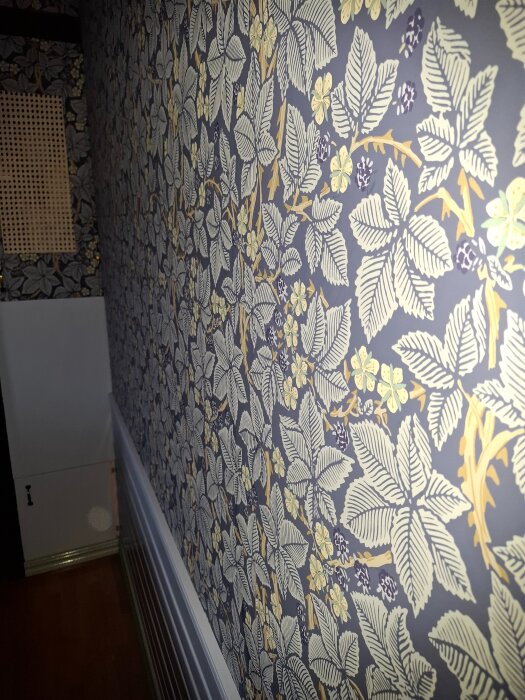 Närbild av en vägg tapetserad med blommönster i blått och gult.