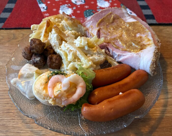 Tallrik med rester: köttbullar, prinskorvar, gratäng, skinka med senap, ägghalva med räkor och sallad.