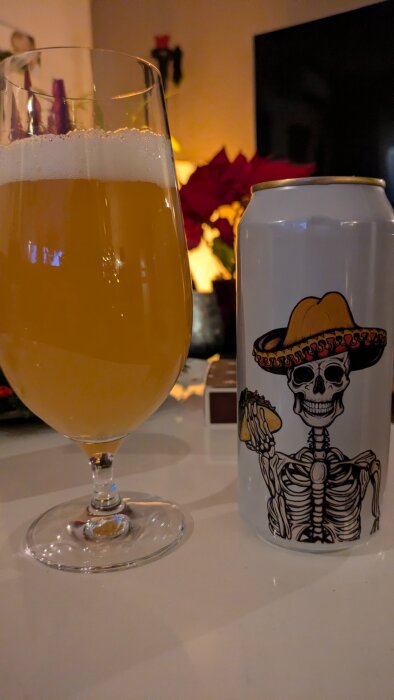 En ölburk med ett skelett i sombrero och en glas öl på ett bord, juldekorationer i bakgrunden.