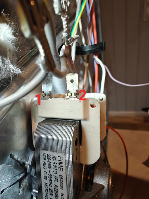 Kopplingsdetalj av en elektrisk motor med märkningar 1 och 2, samt flera anslutna kablar i olika färger.
