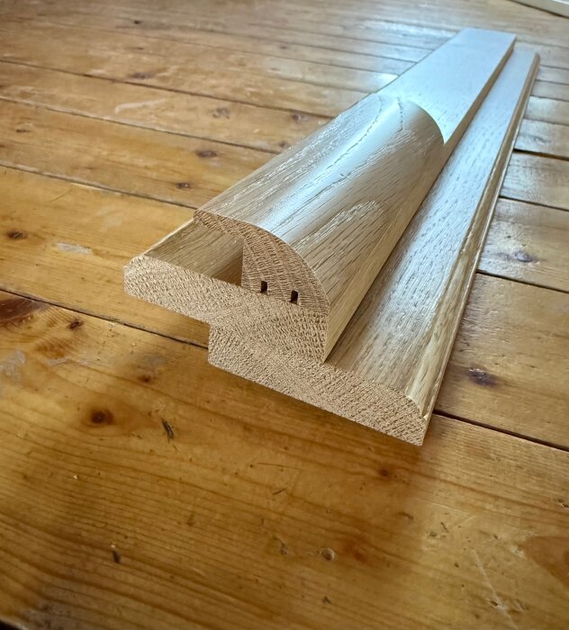 Träpaneler och en trälist ligger staplade på ett trägolv, redo för installation eller renovering.