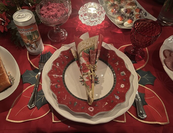 Juldukning med röd och vit tallrik, servett med julmotiv, rödbetssallad i skål, julmustburk, röda glas och ägghalvor med topping på röd duk.