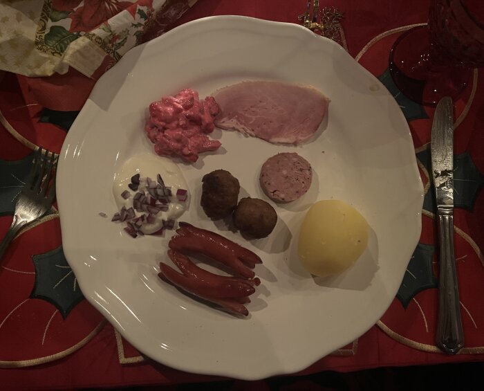 Tallrik med skinka, rödbetssallad, potatis, senapssås med rödlök, korvar och köttbullar på julbord.