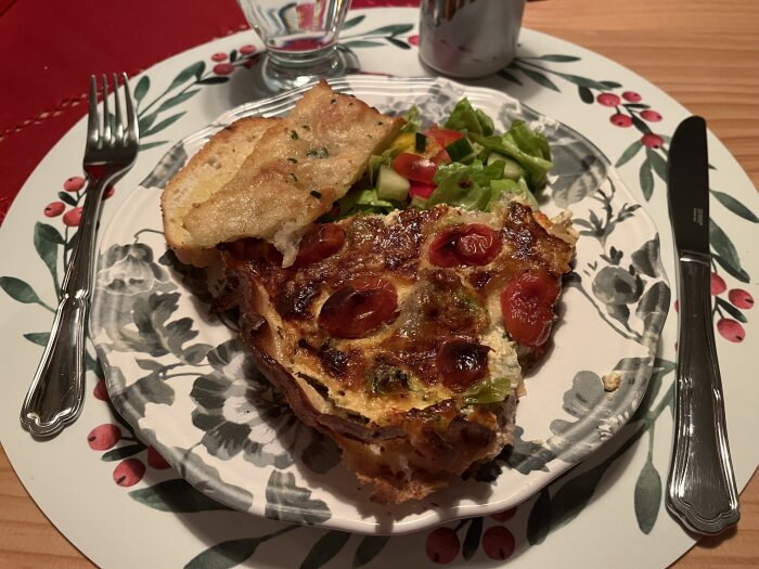 Paj med fläskfilé, broccoli, ost, tomater, lök och gorgonzola serverad på en tallrik med sallad och vitlöksbröd.