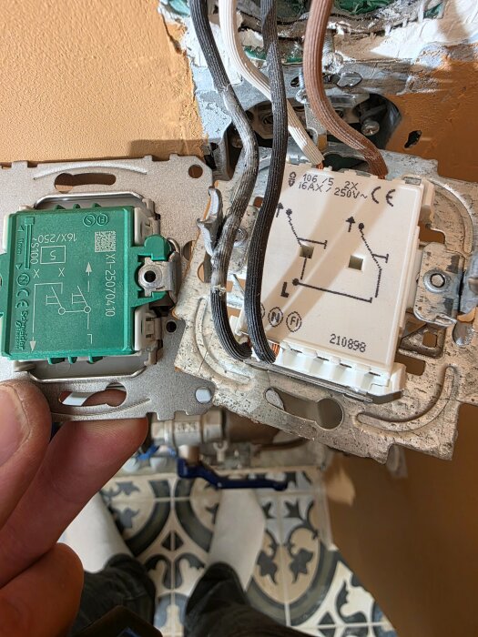 Dubbla kronbrytare, en gammal och en ny, med synliga kablar för byte och koppling i en vägginstallation.