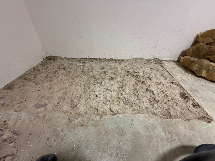 Bortbilad betongsektion i källare efter borttagning av gammal oljetank, med jämnad yta för platonmatta.