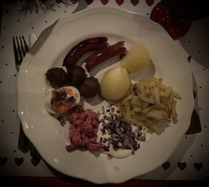 Tallrik med julmat: korvar, köttbullar, kokt potatis, rödbetssallad, ägg med rom, stekt potatis, och hackad lök.